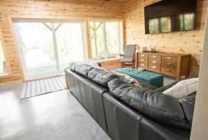 ein Wohnzimmer mit einem Ledersofa und einem TV in der Unterkunft Elk in Audet