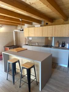 a kitchen with a large counter and two stools at Baita Lomasona in Comano Terme