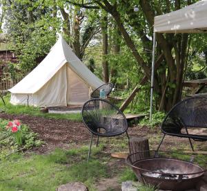 a tent and two chairs and a grill in a yard at Glamping Zonnebloem - Back-to-Nature in Herzele