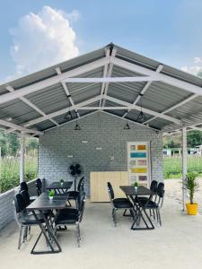 a patio with tables and chairs under a roof at Serene River Cottages Sadhupul in Jūnga +25 photos