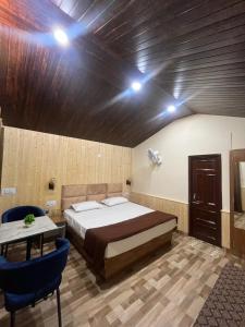 a bedroom with a bed and a table and blue chairs at Serene River Cottages Sadhupul in Jūnga +14 photos