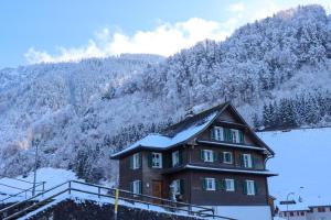 een huis met sneeuw voor een berg bij Afrika Zimmer mit Bergblick in Emmetten