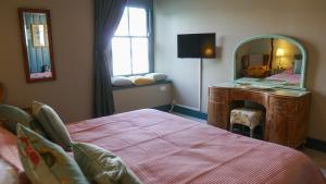 a bedroom with a bed and a dresser and a mirror at The Star in Narberth A Micro Pub with Rooms in Narberth