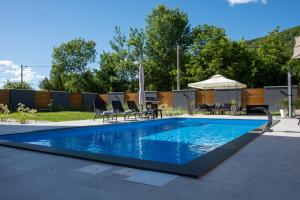 einen Pool mit Stühlen, einem Tisch und einem Sonnenschirm in der Unterkunft Villa of Senses in Bihać