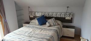 a bedroom with a bed with blue pillows on it at Lama de María in Ourense
