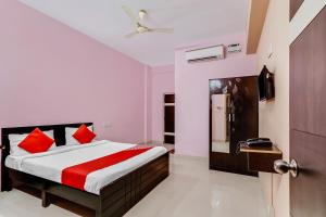a bedroom with a bed with red pillows and a door at Super Hotel O Aaira Inn in Bengaluru