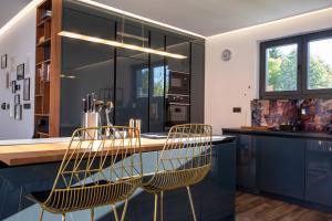 eine Küche mit schwarzen Schränken und goldenen Stühlen in der Unterkunft Villa of Senses in Bihać