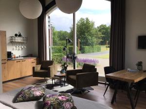 ein Wohnzimmer mit einem Tisch und Stühlen sowie einem großen Fenster in der Unterkunft B&B De Veluwe Hoeve in Eerbeek