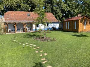 a path in a yard with a house and a tree at Szarvas és Bagoly Kalandház in Szarvas