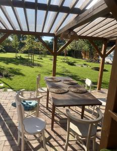 a wooden table and chairs under a wooden pergola at Szarvas és Bagoly Kalandház in Szarvas