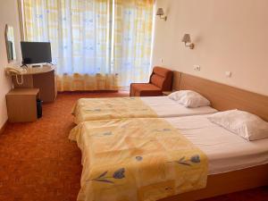 a hotel room with two beds and a television at Vezhen Hotel - Free Parking in Golden Sands