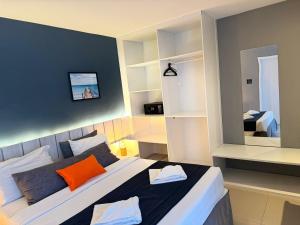 um quarto com uma cama grande e uma almofada laranja em Flat 218 no bairro da Passagem em Cabo Frio em Cabo Frio