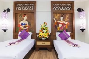 
a hotel room with two beds and two paintings on the wall at Nak Nakara Hotel-SHA Extra Plus in Chiang Rai
