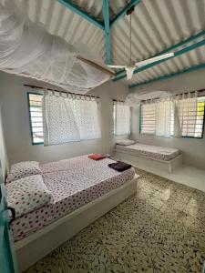 a bedroom with two beds and two windows at Casa Manglar in Tolú