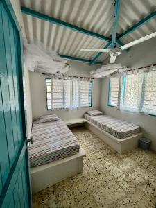 two beds in a room with two windows at Casa Manglar in Tolú