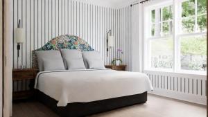 a bedroom with a white bed with a floral headboard at Manoir Hovey, Relais & Châteaux in North Hatley
