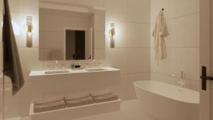 łazienka z 2 umywalkami, wanną i lustrem w obiekcie Manoir Hovey, Relais & Châteaux w mieście North Hatley