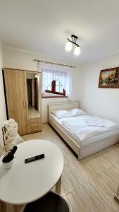a white bedroom with a bed and a table at Gościniec Krys in Żnin
