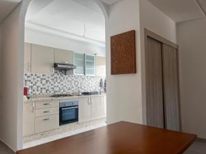 a kitchen with white cabinets and a wooden table at Costa Mar, Playa 5 in Martil