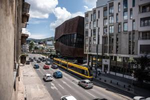 une rue de la ville avec des voitures et un bus jaune dans l'établissement Azzurro City Sarajevo, à Sarajevo
