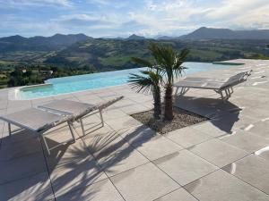 eine Terrasse mit einer Bank und einer Palme neben einem Pool in der Unterkunft Casa Ripa Guest House in Cupramontana