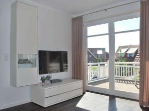 uma sala de estar com uma televisão de ecrã plano e uma varanda em Holiday apartment Marleen em Borkum