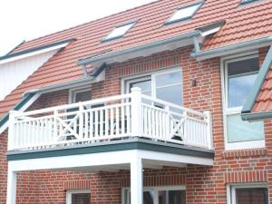 uma casa de tijolos com uma varanda branca em Holiday apartment Marleen em Borkum