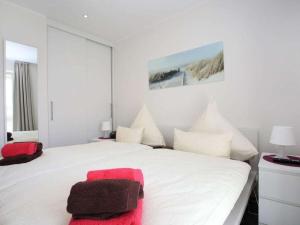 um quarto com uma cama branca com um objecto vermelho em Holiday apartment Marleen em Borkum