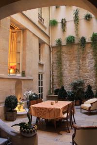 un patio avec une table et des chaises et un bâtiment dans l'établissement La Maison d'Anne, à Paris