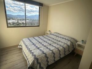 a bedroom with a bed and a large window at Departamento centro Quillota con estacionamiento in Quillota