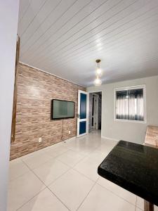 a living room with a brick wall and a flat screen tv at Hostel Ribeirão Dourado in Florianópolis