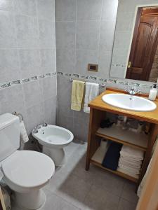 La salle de bains est pourvue de toilettes blanches et d'un lavabo. dans l'établissement Green House, à El Calafate