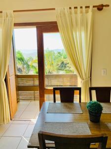 una sala da pranzo con tavolo e una grande finestra di Silveira Eco Village Residence a Garopaba