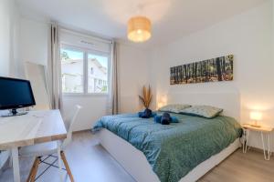 a bedroom with a bed and a desk and a television at Atlantic Selection - Le Duna - Ambiance zen avec terrasse & parking in Capbreton