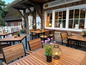 an outdoor patio with wooden tables and chairs and flowers at Landhotel Vessens Hoff in Buchholz in der Nordheide