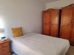 Un dormitorio con una cama con una almohada amarilla y armarios de madera. en Vivienda Turística Argollones 2022, en Almería