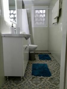 y baño con lavabo, aseo y alfombras azules. en Danais en Atenas