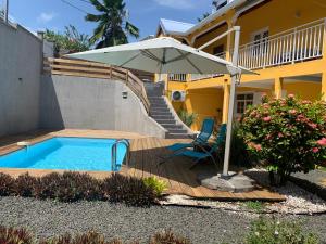 a patio with an umbrella and a chair and a pool at Bas de villa de 3 chambres et spa in Vieux-Habitants