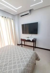 Un dormitorio con una cama y un televisor de pantalla plana. en Hermoso apartamento con vista al mar y la ciudad, en La Romana