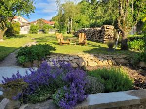 a garden with two wooden chairs and purple flowers at Maison Lombardi - Gite 6 Personnes 4 étoiles in Dun-sur-Meuse