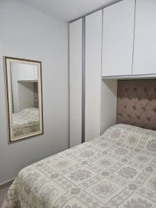 - une chambre avec un lit et un miroir dans l'établissement HollydayAppartment no Centro Rio das Ostras, à Rio das Ostras