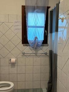 a bathroom with a toilet and a window with a curtain at Sardegna Pittulongu in Olbia +22 photos