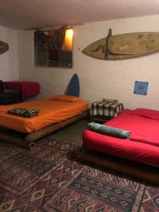 twee bedden in een kamer met een surfplank aan de muur bij Huanchaco Surf Camp in Huanchaco