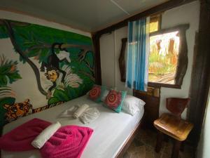 een slaapkamer met een bed met een schilderij aan de muur bij Eco Hostal La Perla Tayrona in El Zaino