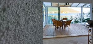 a dining room with a table and chairs on a balcony at Apartman PITOSPORA in Klek