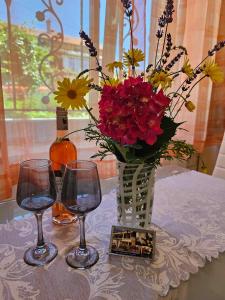 uma mesa com um vaso de flores e dois copos de vinho em Apartmani Rita Oliva em Novigrad Istria