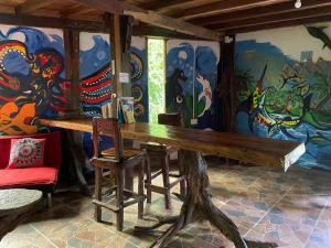 een tafel en stoelen in een kamer met een muurschildering bij Eco Hostal La Perla Tayrona in El Zaino