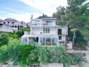 a white house on a hill with trees at Apartman PITOSPORA in Klek