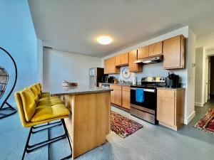 a kitchen with wooden cabinets and a yellow stool at Swanky Loft Near Kings Island, Brewery, Bike Trail in Maineville