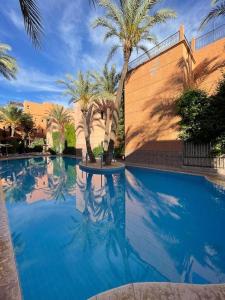 basen z palmami i budynek w obiekcie Riad les fleurs de Lys de Al qaria Assiyahia w Marakeszu